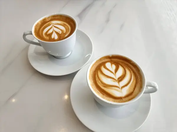 İki fincan sıcak latte sanat lale kahvesi.