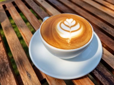 Yandan kahve, bir fincan sıcak latte sanat eseri, ahşap arka planda basit lale kahvesi..