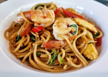 Baharatlı deniz mahsullü spagetti (spagetti Kee Mao talay) beyaz tabakta.