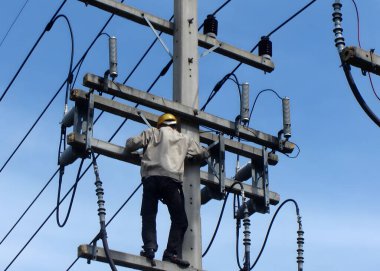 Elektrikçiler, porselen 22kV çalıları temizlemek için elektrik direği üzerinde çalışıyorlar.