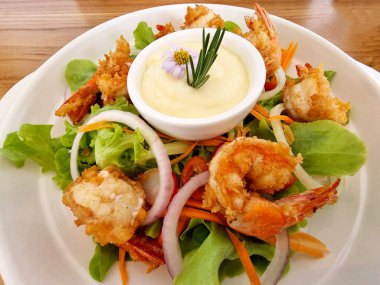 Beyaz tabakta tartar soslu kızarmış karides salatası..