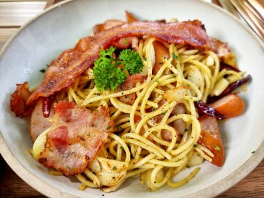 Baharatlı spagetti kuru biberli sarımsaklı pastırma ve beyaz tabakta sosis..