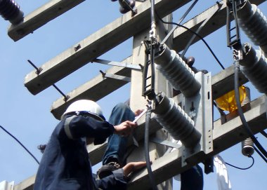 The electrician is working on the electric post power pole to tighten the connection of the disconnecting switch. clipart