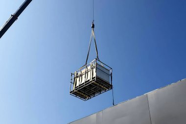 Fotovoltaik güneş panelleri Crane kamyonlarıyla bir fabrika binasının çatısına taşınıyor.