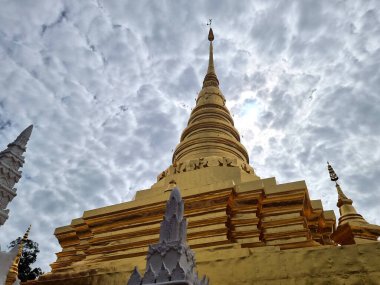 Tayland 'ın Nan Eyaleti' nde Chae Haeng 'in Wat Phra' nın arka planında bulutların üzerindeki güzel, uzun, altın renkli çedi 'nin perspektifi..