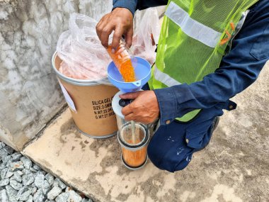 Orange Silica Gel replacement activity for Silica Gel Breather of 115kV/22kV power transformer., Transformer preventive maintenance. clipart