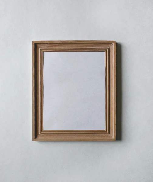 Beyaz duvarda boş tahta, dikdörtgen resim çerçevesi ve içinde boş kağıt var. Görüntüyü bu çerçeveye yerleştirebilirsiniz. İç mekan fotoğrafı. Resim, poster, fotoğraf. Daireni dekore et.