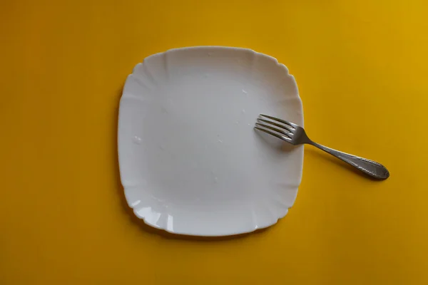 Beyaz tabakta çelik çatal ve mutfakta sarı masa. Ev yapımı yiyecekler, koruma, sebzeler, sosyal yardımlar, sağlık. Kafeler, restoranlar, yemek şirketleri, şef