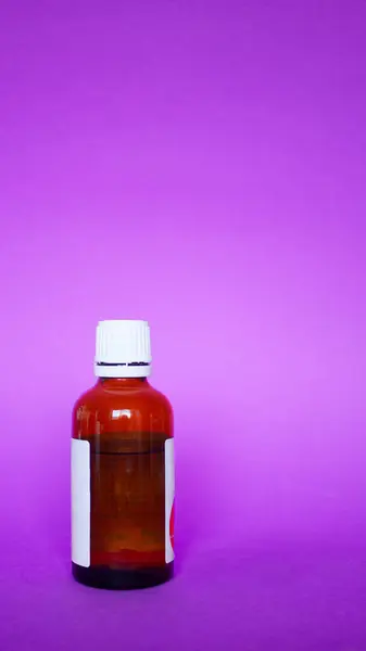 A transparent bottle with medicines. Medicinal liquid, drops. On a bright colored background. Horisontal photo. Hospitals, doctors, health, medicine, self-care