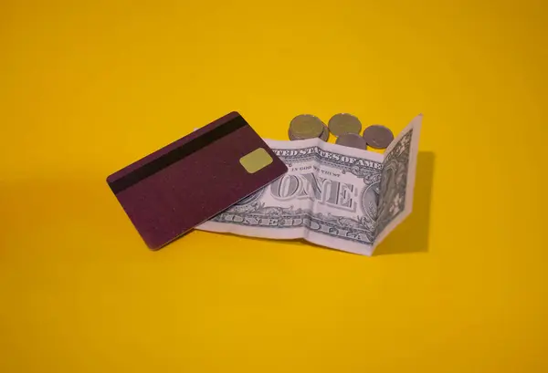 Finansal okuryazarlık. Para transferleri. Yoksulluk. Zenginlik. Farklı şekillerde ödeme. Kredi kartı, bir dolarlık banknot ve sarı arka planda çeşitli paralar. İş projesi. Bağışlar. Jenerik
