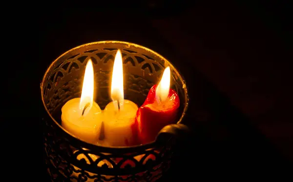 Metal bir mum tutacağında desenleri olan mumlar. Karanlıkta aydınlık. Oda ışıkları. Elektrik kesintisi. Dini tema. Enerjinin konusu. Kurtarıyorum. Hayatta kalmak. Ukrayna 'daki hayatın gerçekleri