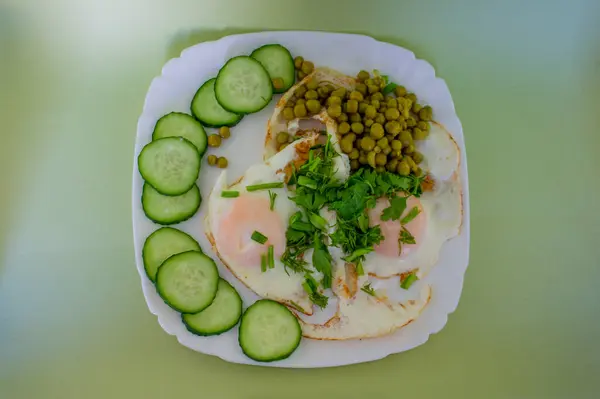 Bezelyeli omlet, soğan, taze salatalık, yeşillikler, beyaz kare bir tabakta salata ve yeşil bir zemin. Restoranlar, kafeler, işletmeler, aşçı, garson, dağıtım, yemek.