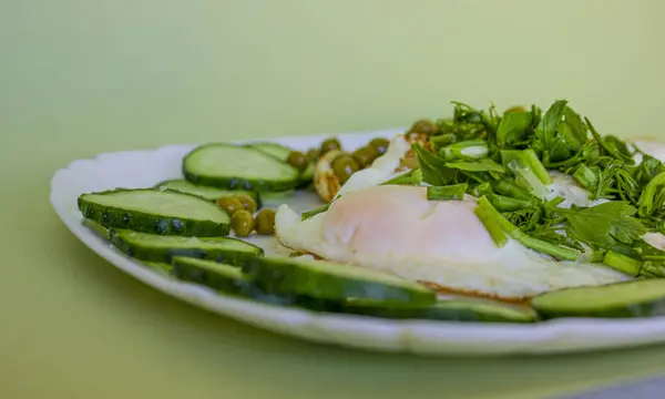 Bezelyeli omlet, soğan, taze salatalık, yeşillikler, beyaz kare bir tabakta salata ve yeşil bir zemin. Restoranlar, kafeler, işletmeler, aşçı, garson, dağıtım, yemek.