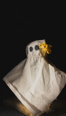 Kafalarında sarı çiçekler olan beyaz peçetelerden yapılmış şirin hayaletler. Cadılar Bayramı 'nı kutlarız. Ürkütücü bir sonbahar. El yapımı.