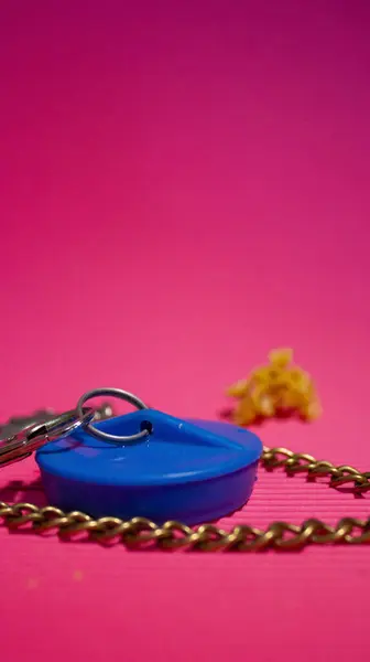 Mavi banyo tıkacı. Lastikten yapılmış. Elinde zincirle. Parlak pembe arka plan. Banyo, hijyen, ev aletleri. Tesisat