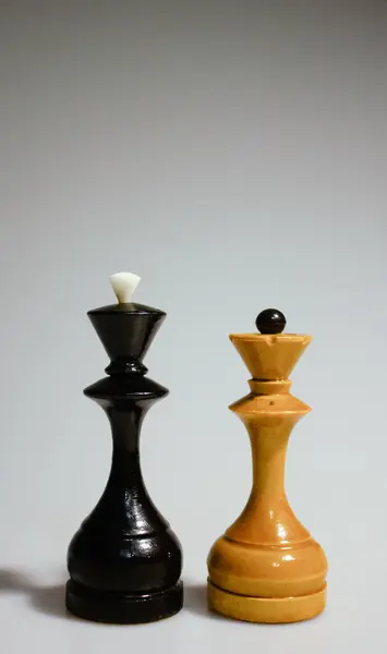 Beyaz arka planda kral ve kraliçenin satranç taşları. Beyin oyunu. Aile, hobi, spor, turnuva. Dikey, portre