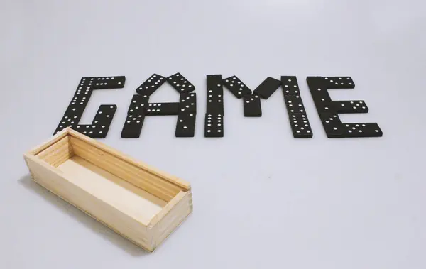 Domino oyunu. Noktaları ve numaraları olan yazıt oyunu. Beyaz arka planda siyah figürler ve tahta bir kutu. Aile eğlencesi ve ilginç bir eğlence. Arkadaşla zihin sporu.