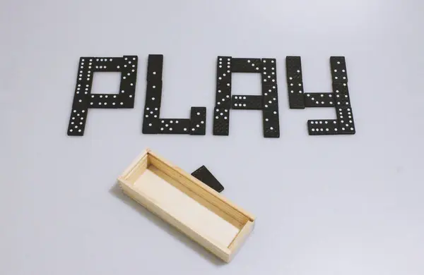 Domino oyunu. Yazı, üzerinde noktalar ve sayılar olan figürler ile oynar. Beyaz arka planda siyah figürler ve tahta bir kutu. Aile eğlencesi ve ilginç bir eğlence. Arkadaşla zihin sporu.