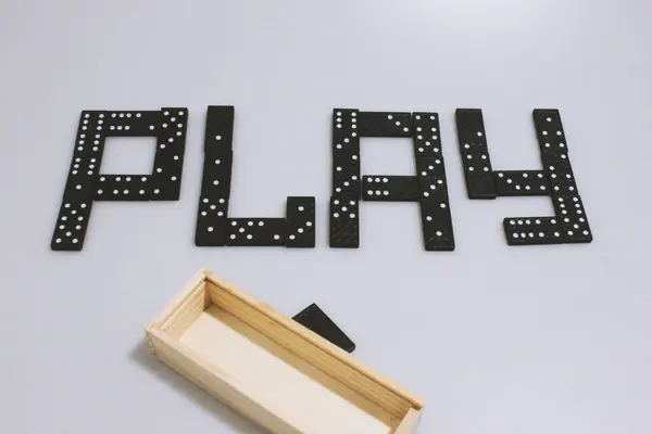 Domino oyunu. Yazı, üzerinde noktalar ve sayılar olan figürler ile oynar. Beyaz arka planda siyah figürler ve tahta bir kutu. Aile eğlencesi ve ilginç bir eğlence. Arkadaşla zihin sporu.
