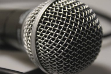 Konser mikrofonu, ses kablosu, gümüş metal örgülü siyah. Beyaz bir arka planda. Yakın plan. Vokaller, şarkılar, podcastlar ve yayınların stüdyo kayıtları için.