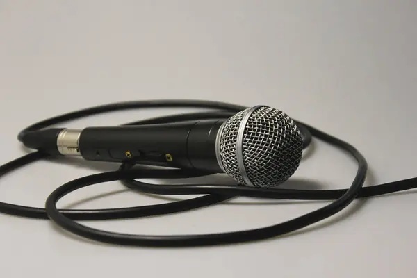 Konser mikrofonu, ses kablosu, gümüş metal örgülü siyah. Beyaz bir arka planda. Yakın plan. Vokaller, şarkılar, podcastlar ve yayınların stüdyo kayıtları için.