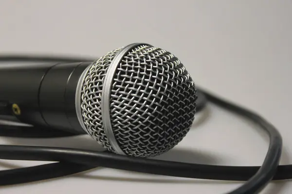 Konser mikrofonu, ses kablosu, gümüş metal örgülü siyah. Beyaz bir arka planda. Yakın plan. Vokaller, şarkılar, podcastlar ve yayınların stüdyo kayıtları için.