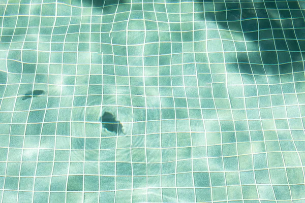 Water surface with waves on water surface wave effect You can see the blue square tiles at the bottom of the pool.
