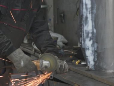 Öğütücüyle metal kesen bir işçi. Sanayi atölyesinde demir öğütürken kıvılcımlar çıkıyor. Makedonya 'nın Kocani kenti yakınlarında