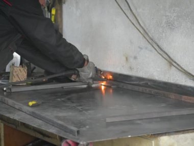 İşçi, kaynakçı, iş kıyafetleri, inşaat eldivenleri ve bir kaynak maskesiyle kaynak makinesi, Kocani Makedonya yakınlarındaki atölye çalışmasında kullanılıyor.