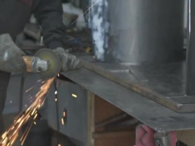 Öğütücüyle metal kesen bir işçi. Sanayi atölyesinde demir öğütürken kıvılcımlar çıkıyor. Makedonya 'nın Kocani kenti yakınlarında
