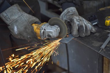 Öğütücüyle metal kesen bir işçi. Sanayi atölyesinde demir öğütürken kıvılcımlar çıkıyor. Makedonya 'nın Kocani kenti yakınlarında
