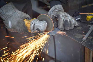 Öğütücüyle metal kesen bir işçi. Sanayi atölyesinde demir öğütürken kıvılcımlar çıkıyor. Makedonya 'nın Kocani kenti yakınlarında