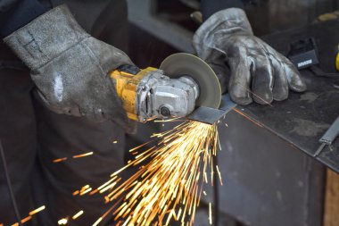 Öğütücüyle metal kesen bir işçi. Sanayi atölyesinde demir öğütürken kıvılcımlar çıkıyor. Makedonya 'nın Kocani kenti yakınlarında
