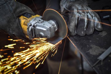Öğütücüyle metal kesen bir işçi. Sanayi atölyesinde demir öğütürken kıvılcımlar çıkıyor. Makedonya 'nın Kocani kenti yakınlarında