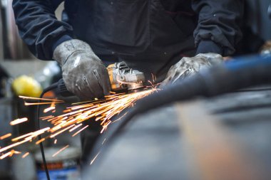Öğütücüyle metal kesen bir işçi. Sanayi atölyesinde demir öğütürken kıvılcımlar çıkıyor. Makedonya 'nın Kocani kenti yakınlarında