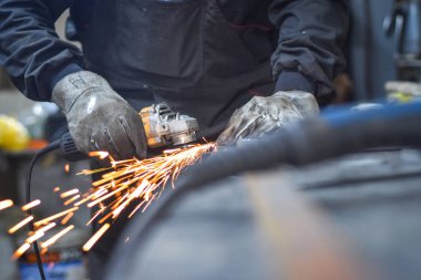 Öğütücüyle metal kesen bir işçi. Sanayi atölyesinde demir öğütürken kıvılcımlar çıkıyor. Makedonya 'nın Kocani kenti yakınlarında