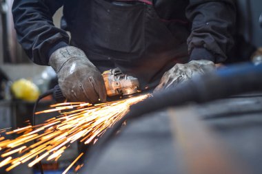 Öğütücüyle metal kesen bir işçi. Sanayi atölyesinde demir öğütürken kıvılcımlar çıkıyor. Makedonya 'nın Kocani kenti yakınlarında