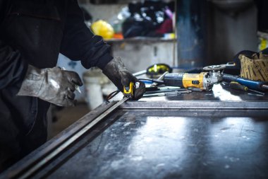 Endüstriyel atölyede metal bar ölçümleri yapan bir işçi. Kocani Makedonya yakınları