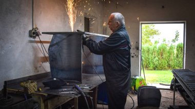Öğütücüyle metal kesen bir işçi. Sanayi atölyesinde demir öğütürken kıvılcımlar çıkıyor. Makedonya 'nın Kocani kenti yakınlarında