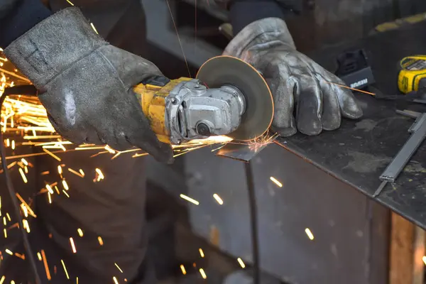 Öğütücüyle metal kesen bir işçi. Sanayi atölyesinde demir öğütürken kıvılcımlar çıkıyor. Makedonya 'nın Kocani kenti yakınlarında