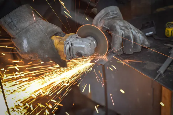 Öğütücüyle metal kesen bir işçi. Sanayi atölyesinde demir öğütürken kıvılcımlar çıkıyor. Makedonya 'nın Kocani kenti yakınlarında