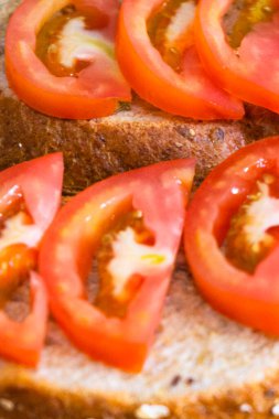 Domates dilimlerini susamlı ekmek dilimine yakın tut.