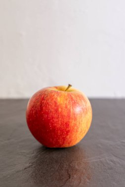 Arka planda beyaz bir duvar olan siyah bir arka planda kırmızı elma.
