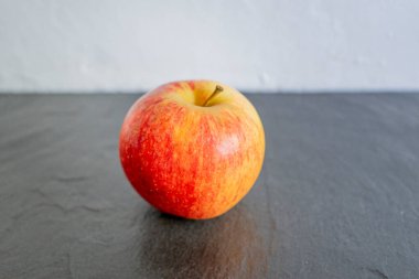 Siyah plakalı kırmızı elma, beyaz duvar arka planı, stok fotoğrafı.