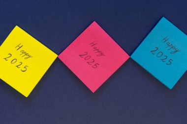 Yapışkan bir nottaki motivasyon mesajında mavi arka planda fotokopi alanı ile mutlu 2025 yazılıydı..