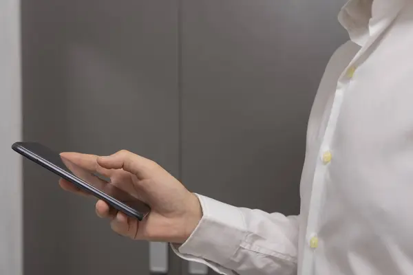 Otel odasında cep telefonu kullanan bir kadın. Akıllı telefon tutan bir kadının yakın çekimi..