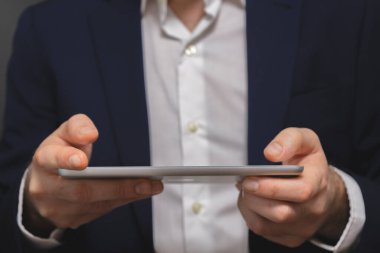 Gri arkaplanda dijital tablet kullanan işadamı, ellerin kapatılması
