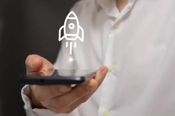 İş adamı ekranında roket simgesi olan bir akıllı telefon tutuyor..