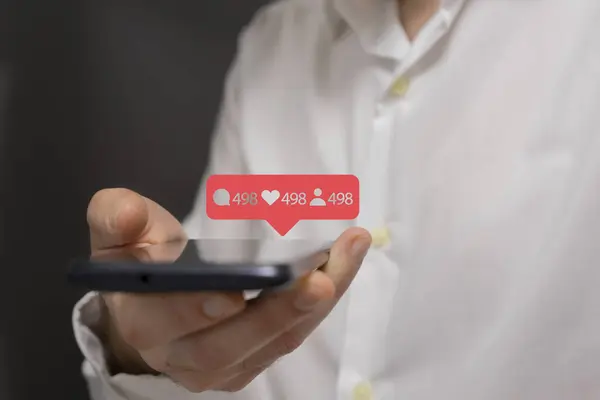 Ekranda sosyal medya uygulama simgesi olan akıllı telefonu tutan adam.