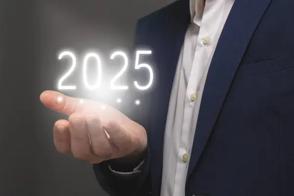 İş adamı, gri arka planda 2025 yılını gösteriyor. Yeni yıl kavramı